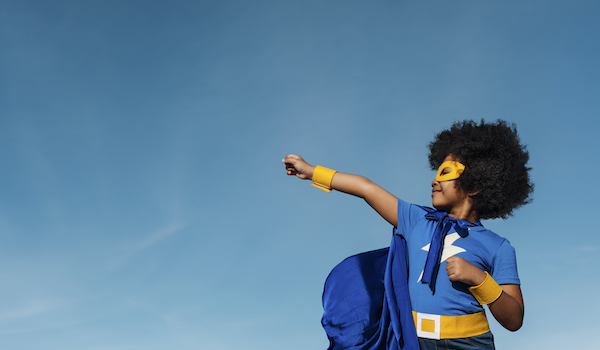 Girl with afro in superhero costume doing powerful pose