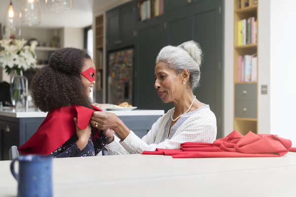 Superhero grandaughter being dressed by her grandmother